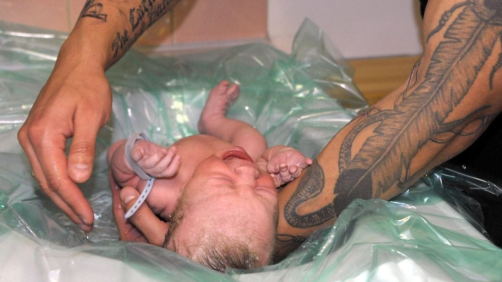 Tuore isä pitelee vastasyntynyttä lasta Kätilöopistolla Helsingissä.