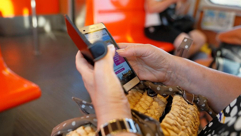 Metromatkustaja selasi internetiä älypuhelimellaan. Kuvituskuva.