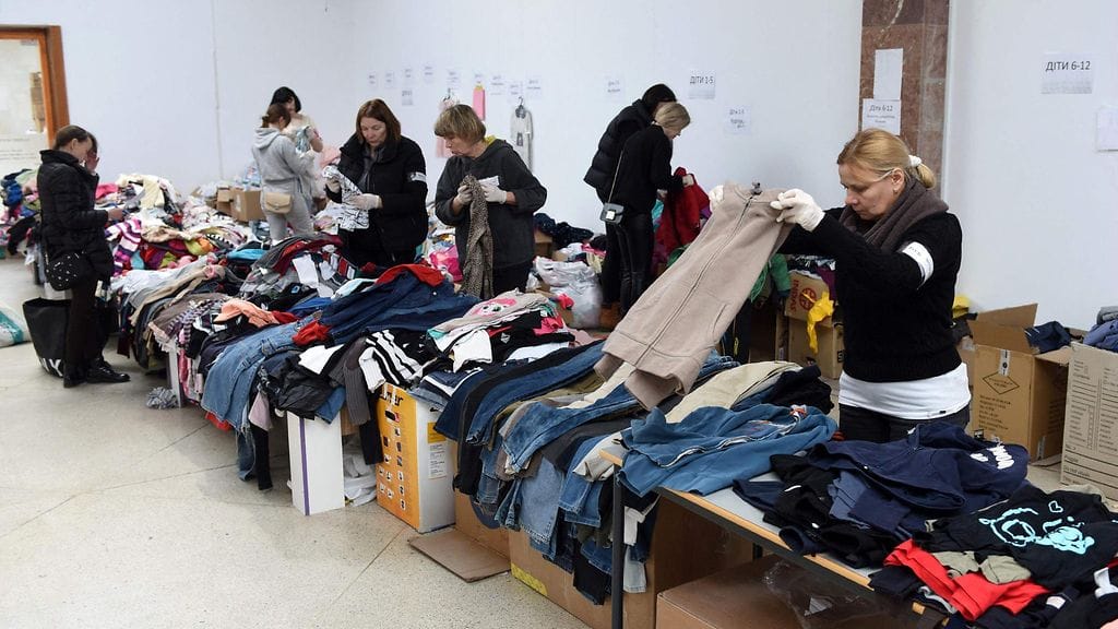 Kuvassa vapaaehtoiset lajittelevat pakolaisille lahjoitettuja vaatteita Lvivin kaupungissa.