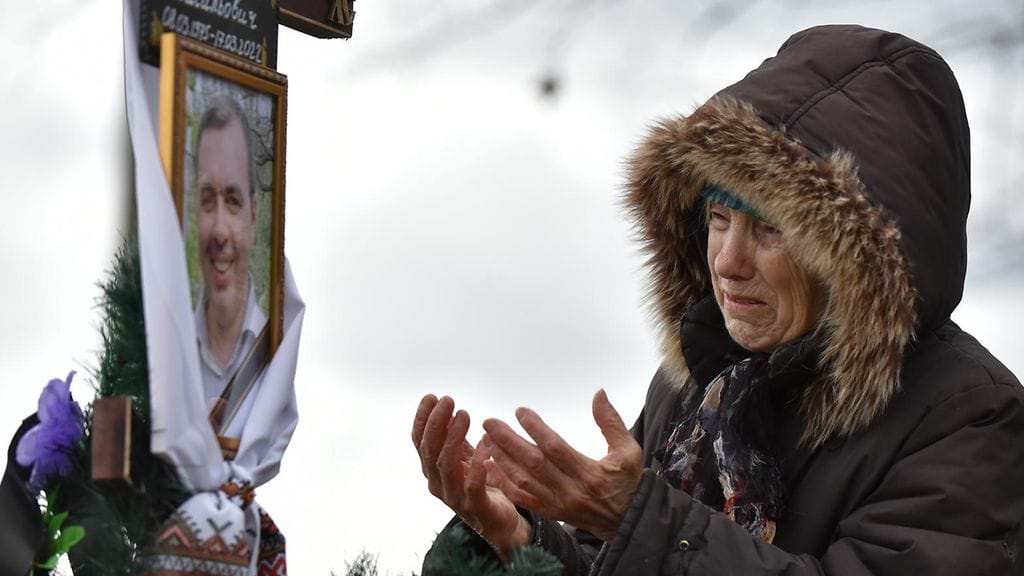 Ukrainalainen äiti itkee poikansa haudalla huhtikuussa 2022.