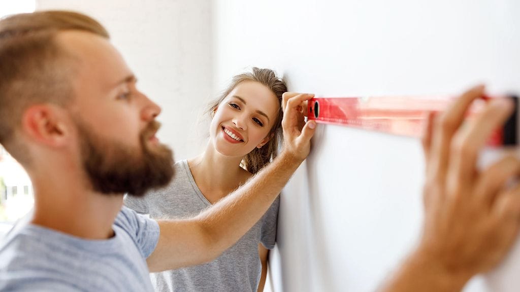 mies mittailee seinää ja nainen ihailee