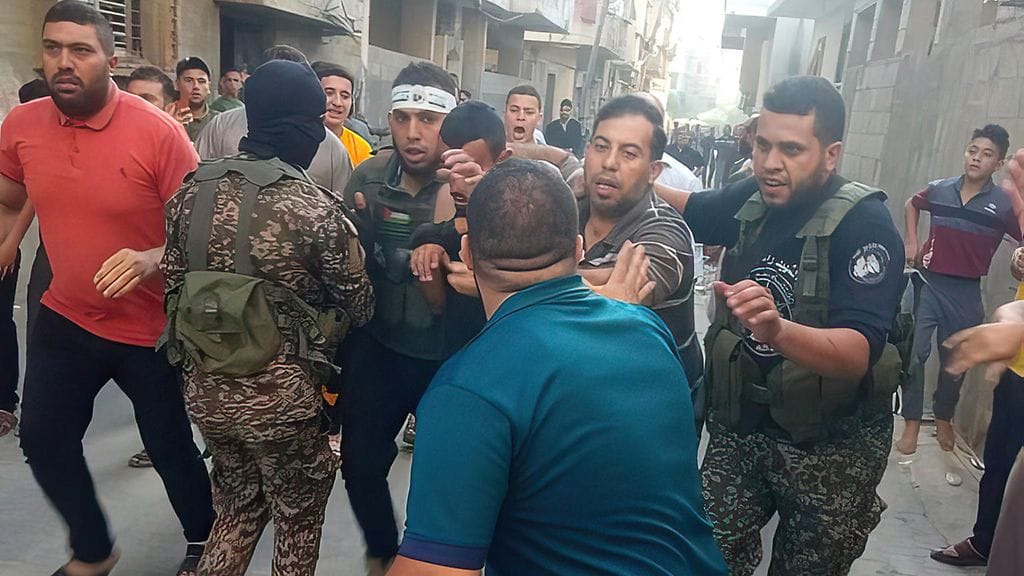 Hamasin taistelijoita ottamassa israelilaista miestä kiinni Gazassa viikonloppuna. Washington Postin mukaan Hamas on jo teloittanut panttivankejaan.