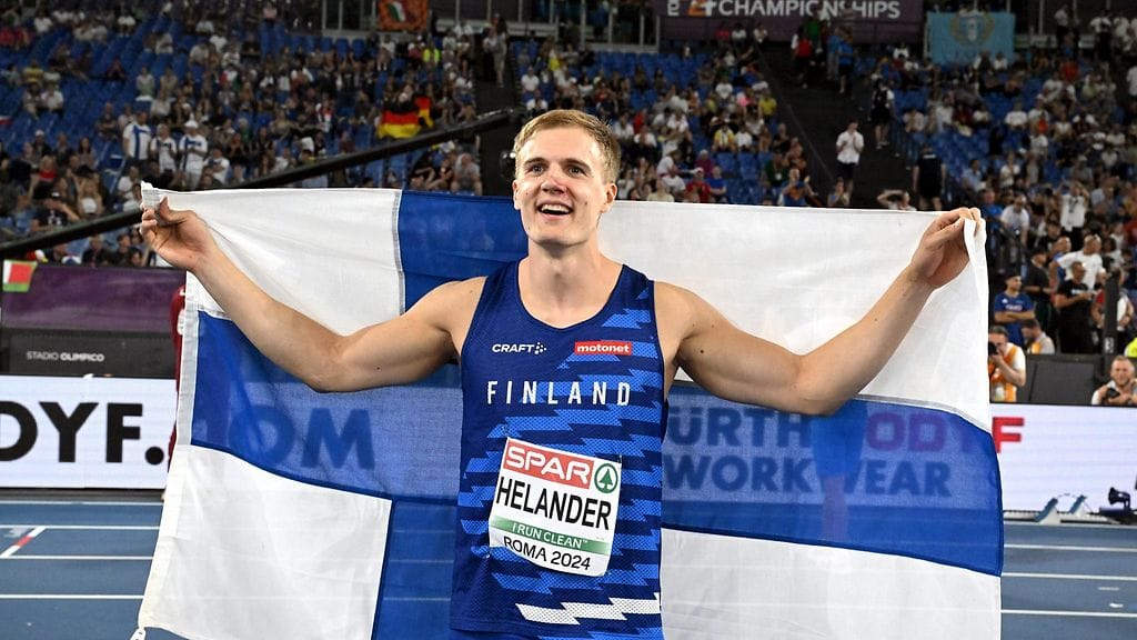 Oliver Helander juhli kentällä EM-pronssia Suomen lipun kanssa.