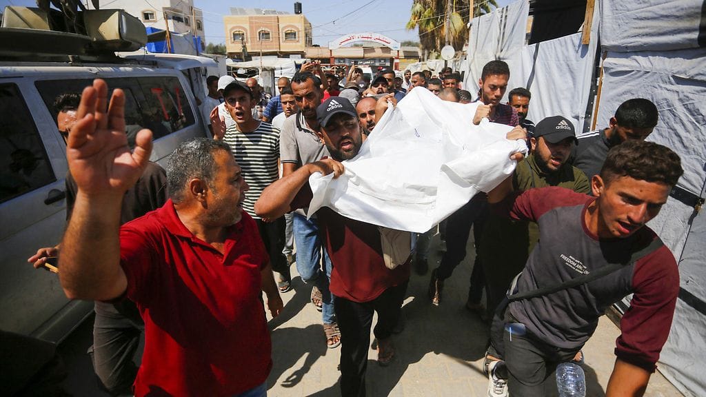 Ihmiset siirtävät avustustyöntekijän ruumista perjantaina 12. heinäkuuta.