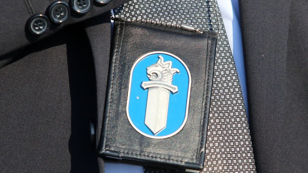 Poliisin virkamerkkikotelo, jossa myös poliisin hihamerkkiä muistuttava metallinen tunnuskuva. Kuvituskuva.