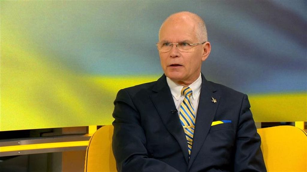 Jarmo Lindberg puhuu yllään tumma puku ja kaulassaan sini-keltainen kravatti.