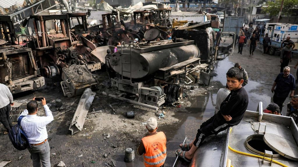 Poika istuu vesisäiliöauton päällä, kun muut miehet tarkastavat tuhoutuneita ajoneuvoja Israelin pommitusten kohteeksi joutuneessa Jablassa tiistaina 22.4.2025.