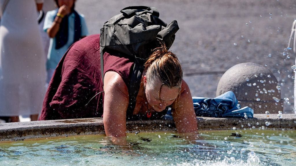 Nainen viilentäytyy roomalaisella suihkulähteellä 6. heinäkuuta 2025 lämpötilojen hipoessa 40 astetta.