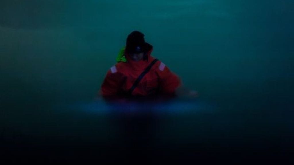 Erikoissuunnittelija Anu Lastumäki Suomen ympäristökeskuksesta näyttää, miten panssarisiimalevän bioluminesenssi tulee esiin, kun vettä liikutetaan. Useimmiten ilmiön havaitsee esimerkiksi veneillessä tai uidessa.