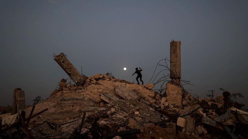 Nuori ihminen leikki raunioilla Gazassa vuoden viimeisen superkuun noustessa Nuseiratin leirin ylle 4. joulukuuta.