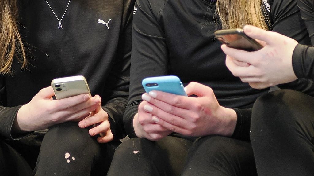 Kuvituskuvassa nuoria kännyköiden ääressä.