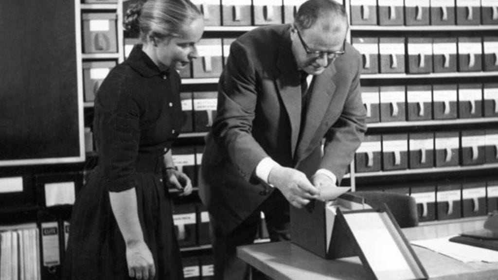 1962: Suomen Akatemian jäsen, professori Kustaa Vilkuna tarkastelee assistenttinsa kanssa paikannimiarkiston kortteja. Kuva on säästöpankkien akateemikkosarjan elokuvasta. LEHTIKUVA / HS